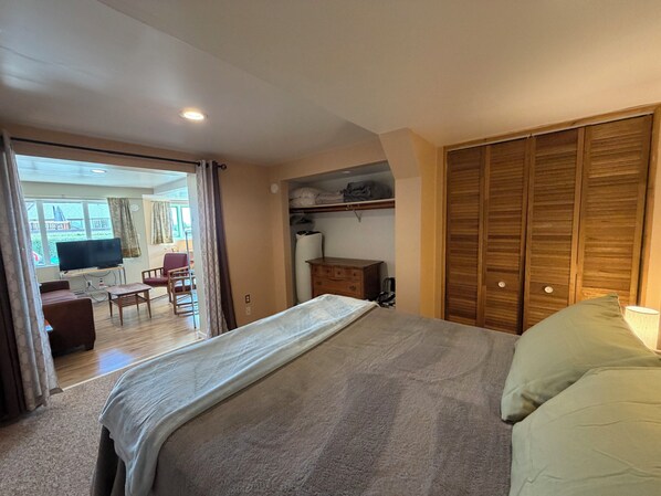 A bedroom with a bed, a TV, a desk, and a wardrobe.