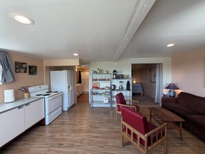 A compact living space with a kitchenette, a dining area with a wooden table and red chairs, and a sofa.