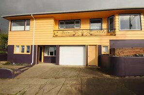A two-story residential building with a garage, a balcony, and a driveway.