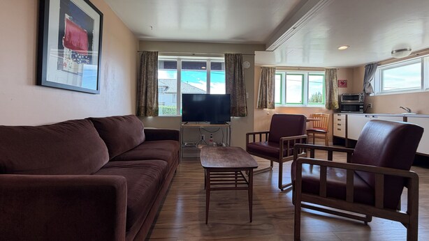 A living room with a sofa, a coffee table, and a TV. There is a kitchen area with a microwave and a sink. - Sunset Studio, Best walkable location in Arcata & Bay View Studio (Arcata)
