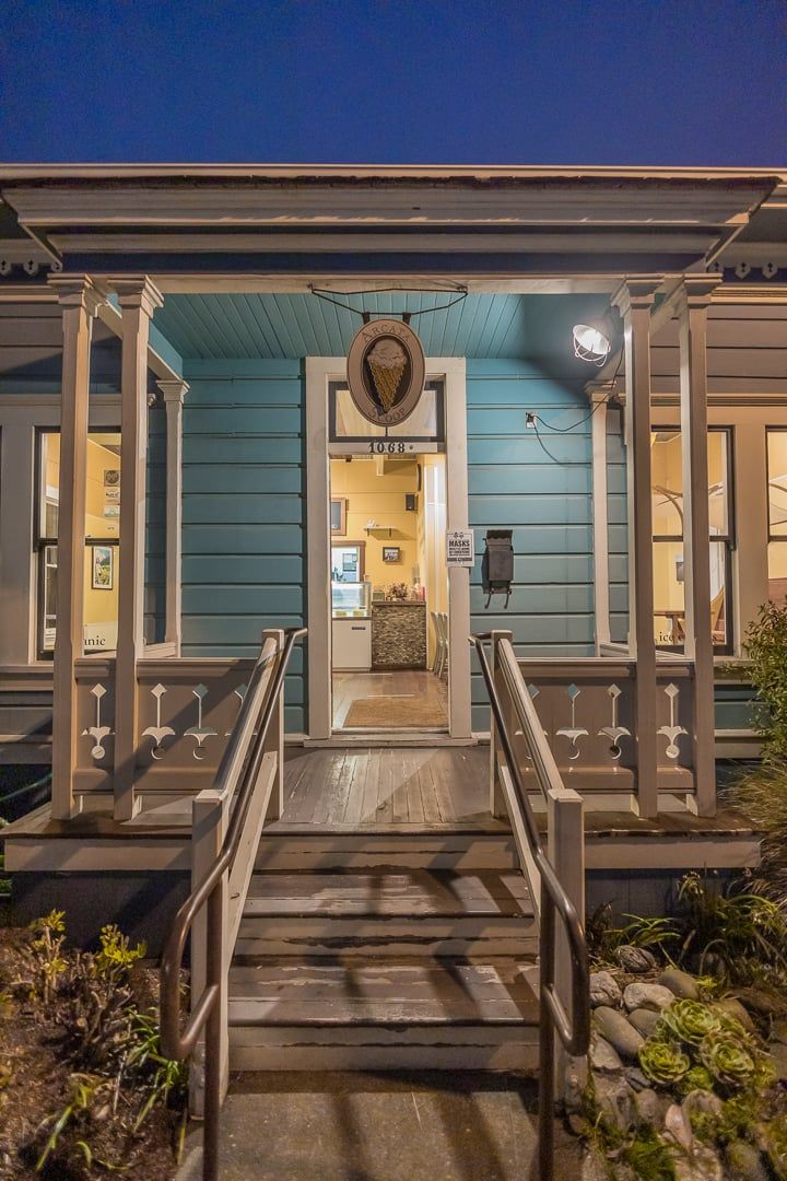 A building with a porch, a staircase leading to the entrance, and a sign above the door.