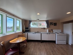 A compact kitchen with a dining table, a stove, and a refrigerator.