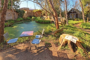 A rustic outdoor area with a pond, wooden structures, and seating.