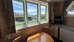 A kitchen with a dining table, chairs, a microwave, and a window with a view of the street. - Sunset Studio, Best walkable location in Arcata & Bay View Studio (Arcata)