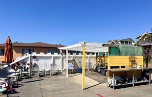 A residential area with a white building, outdoor furniture, and a green container.