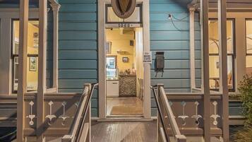 Un edificio con fachada azul, una escalera de madera que lleva a una puerta y un cartel sobre la puerta.