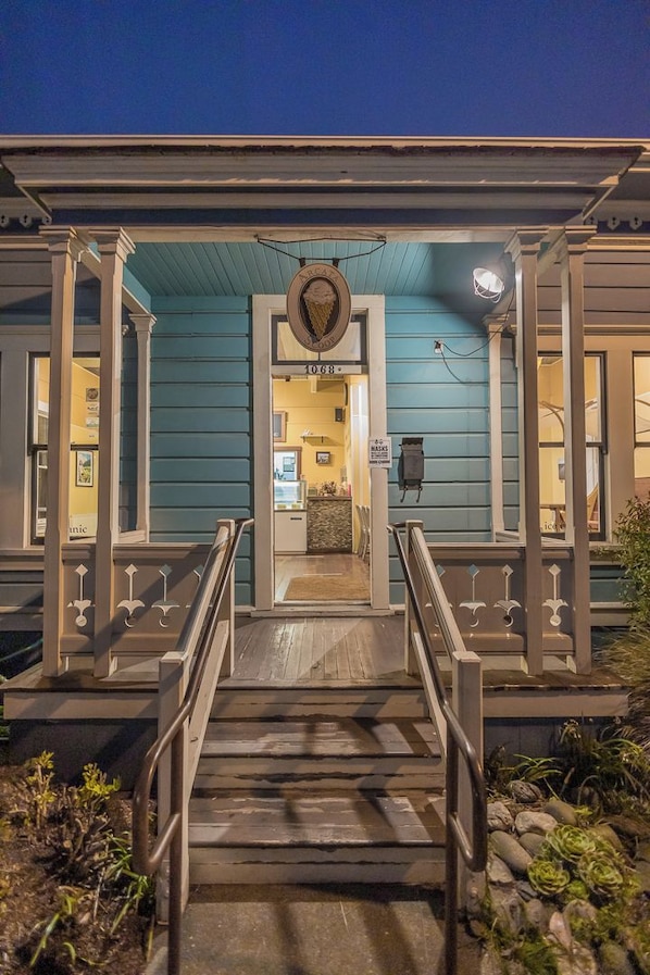 A building with a blue exterior, a wooden staircase leading to a door, and a sign above the door.
