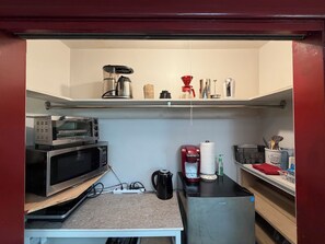 A compact kitchenette with a microwave, coffee maker, and a small refrigerator.
