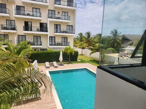 Ein Hotel mit Schwimmbad, mehreren Balkonen und Palmen.