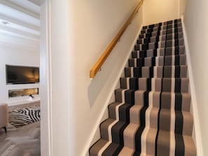 Eine Treppe mit Streifenmuster-Teppich und Holzhandlauf.