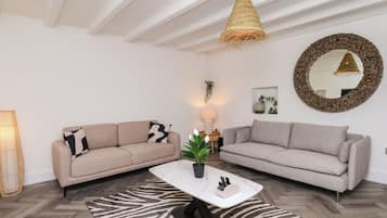 Una sala moderna con dos sofás, una mesa de centro, una lámpara colgante y un espejo decorativo.