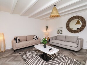 Un saló modern amb dos sofàs, una taula baixa, una làmpada penjant i un mirall decoratiu.