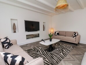 Ein stilvolles Wohnzimmer mit einer Couch, einem Couchtisch, einem Fernseher und Dekoelementen.