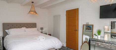 Une chambre d’hôtel avec un lit, une table de chevet, une lampe, un miroir et un téléviseur fixé au mur.