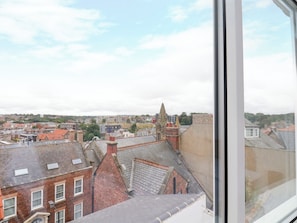 Blick aus einem Fenster auf eine Stadtlandschaft mit verschiedenen Gebäuden, darunter ein markanter Kirchturm.