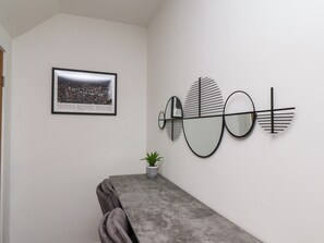 Ein Essbereich mit Tisch, Stühlen, einem gerahmten Stadtbild und einem an der Wand befestigten abstrakten Kunstwerk.