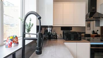 Una cocina moderna con armarios blancos, un microondas negro y un lavamanos de acero inoxidable.
