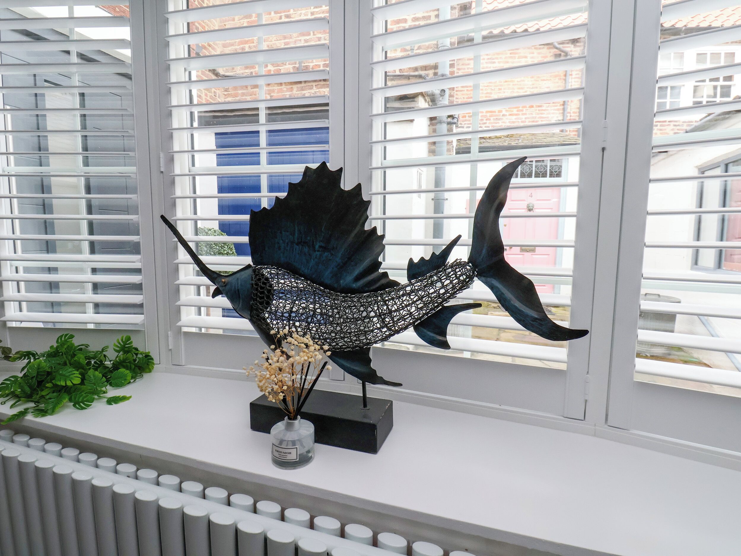 A room with a window, a radiator, and a decorative fish sculpture on a shelf.
