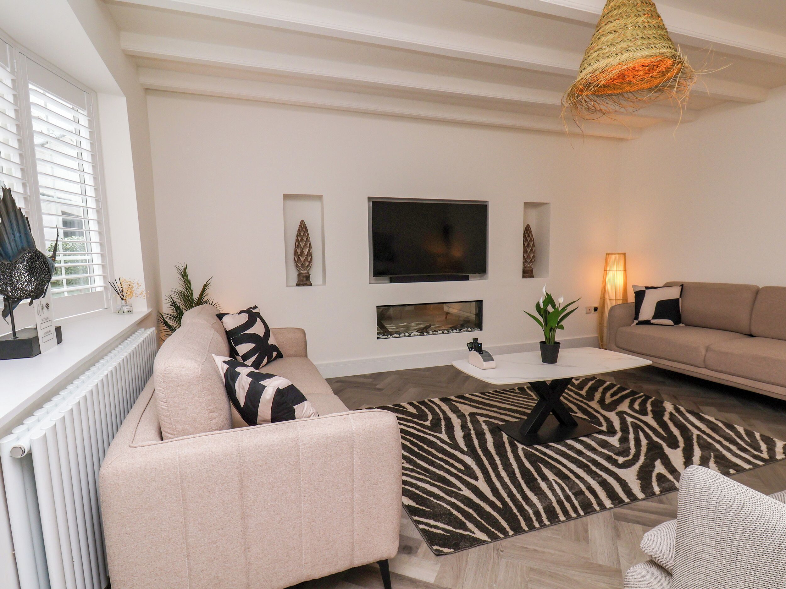 Una sala de estar moderna con un sofá, una mesa de centro, un televisor y una chimenea.