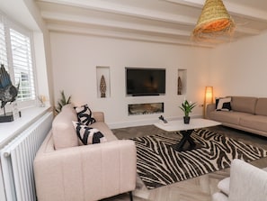 Una sala de estar moderna con un sofá, una mesa de centro, un televisor y una chimenea.