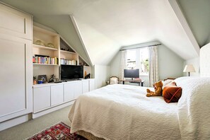 A bedroom with a large bed, a TV, a desk with a computer, and a bookshelf. - A Timeless Family Home (London)