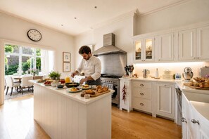 A modern kitchen with a central island, stainless steel appliances, and white cabinetry. - A Timeless Family Home (London)