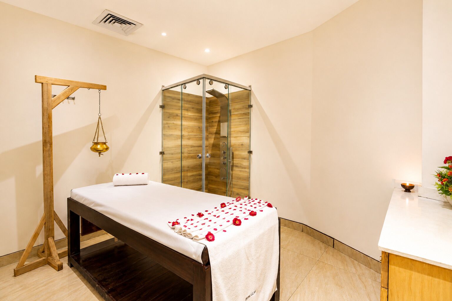 A room with a massage table, a wooden swing, and a glass shower enclosure.