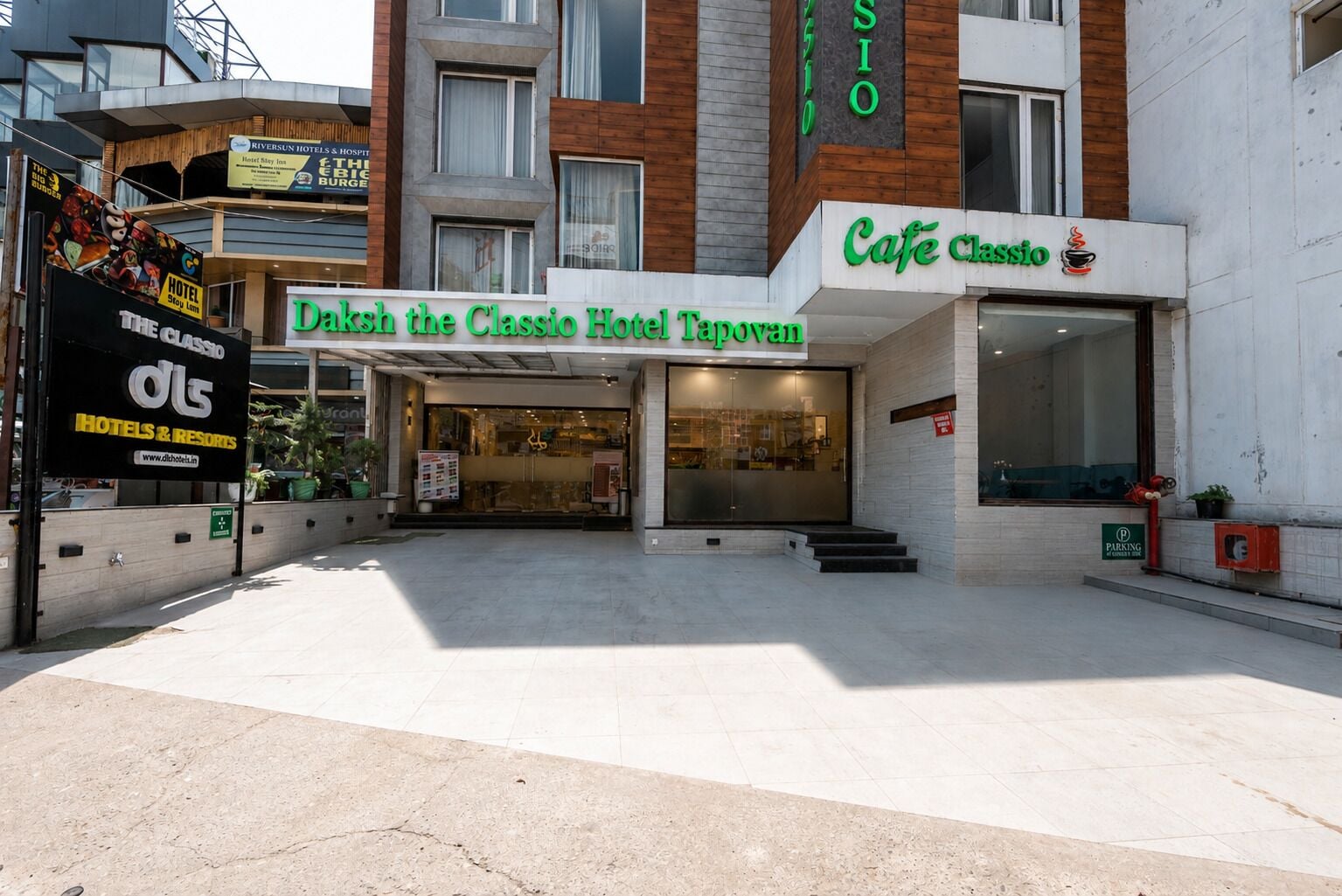 The exterior of Daksh the Classio Hotel Tanovan with a modern facade, a visible entrance, and a cafe named Cafe Classio.