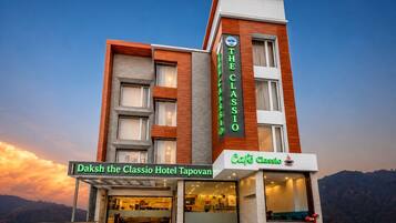 Un hotel con un letrero destacado que dice 'Daksh the Classio Hotel Tapovan' y un café llamado 'Café Classio' en la planta baja.