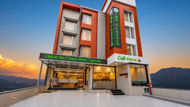 Un hotel con una entrada destacada, un café y vistas a las montañas.