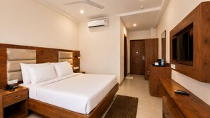 Habitación de hotel con cama, mesita de noche, televisor, armario y equipo de aire acondicionado.