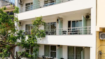Un edificio de varios pisos con balcones, unidades de aire acondicionado y un letrero de restaurante visible.