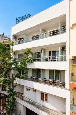 Un edificio de varios pisos con balcones, unidades de aire acondicionado y un letrero de restaurante visible.
