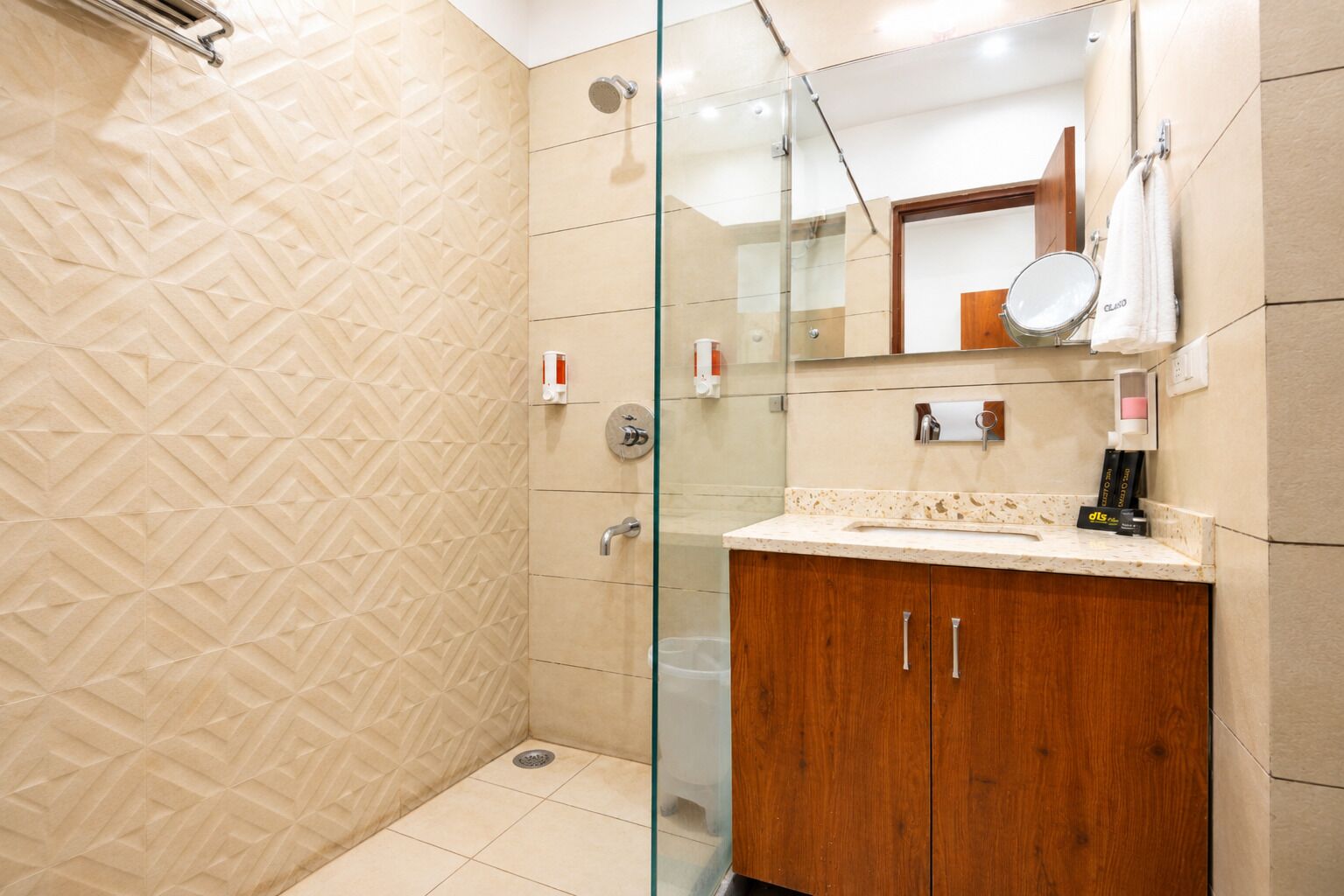 Un baño moderno con cabina de ducha de vidrio, tocador de madera y un espejo sobre el lavamanos.