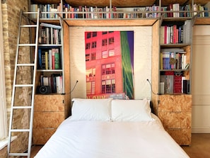 Ein Schlafzimmer mit Hochbett, Holzregalen und einem Stadtplakat.