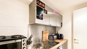 Uma cozinha compacta com forno embutido, pia e cafeteira.