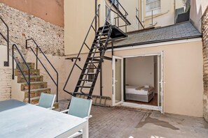 Ein Wohngebäude mit einer Treppe zu einem Schlafzimmer im Zwischengeschoss, einem Essbereich mit Tisch und Stühlen sowie einer Außenwand aus Backstein.