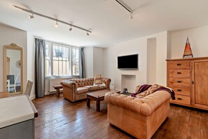 Ein Wohnzimmer mit einer Couch, einem Couchtisch, einem an der Wand befestigten Fernseher und einer Holzkabine.