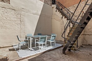 A small outdoor seating area with a table and chairs, a metal staircase, and a brick wall. - Host & Stay | Regency Courtyard (Brighton and Hove)