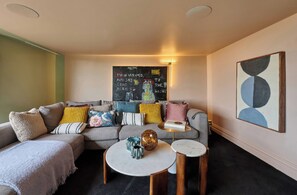 A living room with a sectional sofa, a coffee table, and a small side table. There is a wall-mounted artwork and a framed picture on the wall. - Providence Cottage (Monmouth)