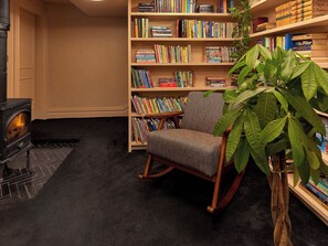 A cozy reading nook with a rocking chair, a bookshelf filled with books, and a fireplace. - Providence Cottage (Monmouth)