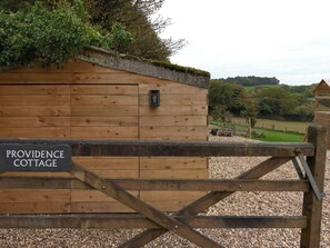 A wooden cottage with a sign reading 'PROVIDENCE COTTAGE' and a gated entrance. - Providence Cottage (Monmouth)