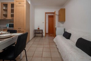 Ein kompakter Wohnbereich mit Küchenzeile, Essplatz und einer Couch.