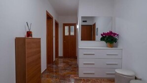 A hallway with a wooden wardrobe, a white dresser with drawers, a mirror, and a potted plant. - Charming Dorsoduro Venice Stay Near Art Museums and Canals (Venezia VE, Italy)