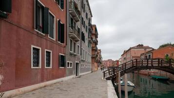 Un canale stretto fiancheggiato da edifici, un ponte di legno e una barca ormeggiata a destra.