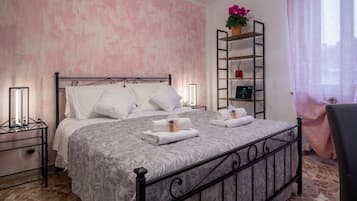 Un letto rifatto con una coperta decorata, un comodino con una lampada e una mensola con oggetti ornamentali.