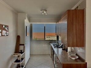 A compact kitchen with a window, a small sink, and a stove. - (026) Le côté Remparts (Antibes)