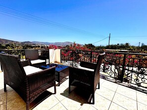 Una terraza con mobiliario de mimbre y vistas a un paisaje montañoso.