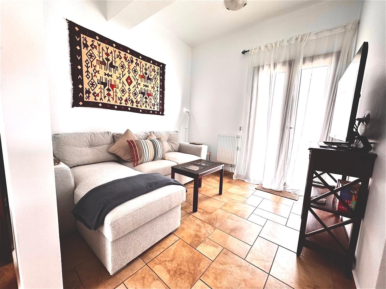 Una sala de estar con sofá, mesa de centro, radiador y estantería.