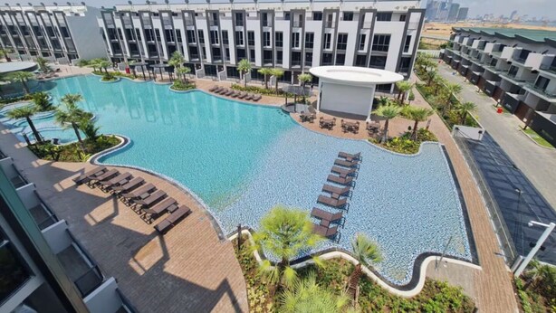 Un hotel moderno con una amplia piscina, tumbonas y vistas del horizonte de la ciudad.
